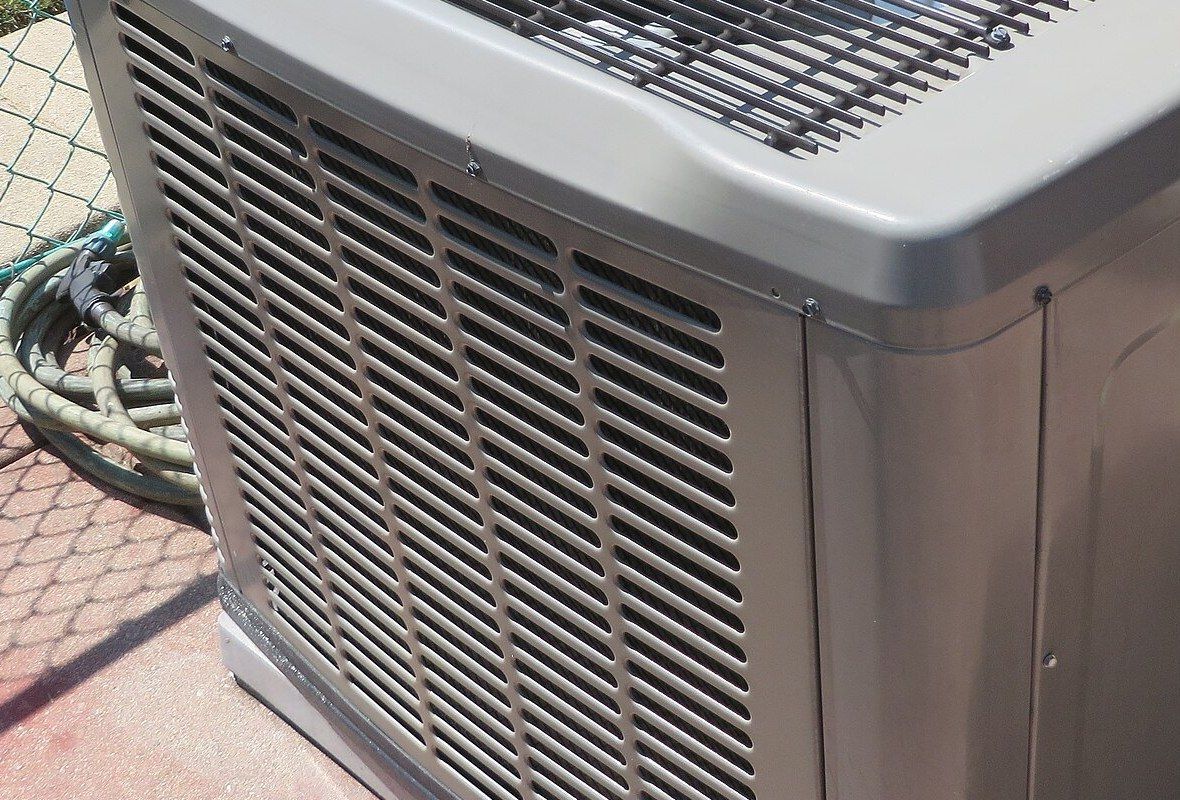 The louvered side of a central air conditioning condenser on its pad