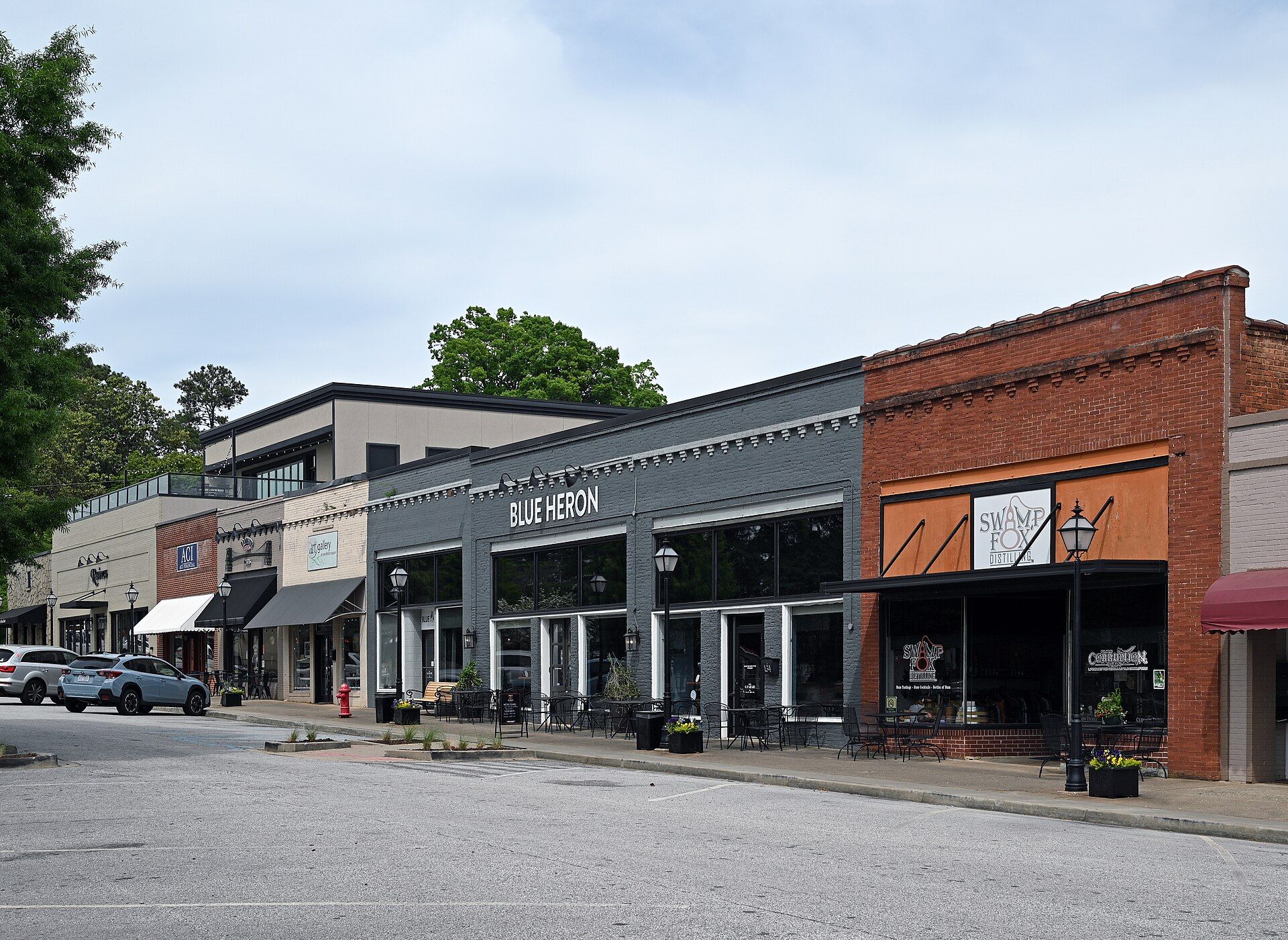 A row of brick shopfronts with awnings, lamp posts and outdoor tables on Exchange Street in Pendleton.